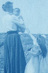 Child reaches for woman holding Baby